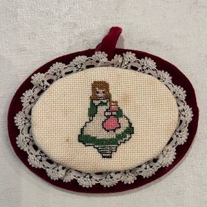 Handmade cross-stitch girl w/ doll backed with plush burgundy velvet.